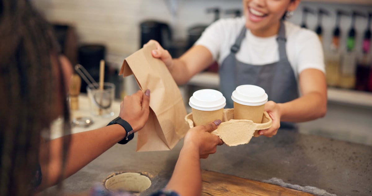 Friendly barista serving a customer a coffee to go